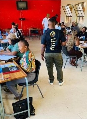 A facilitator walking between desks in a busy classroom